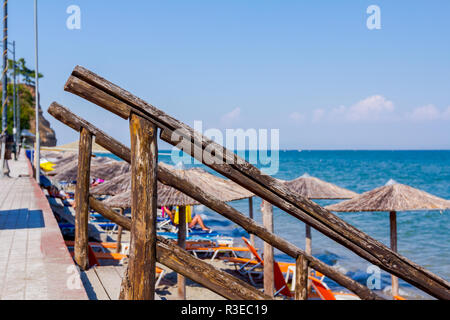 Wooden banister for stairs is going down to the beach from street above. Stock Photo