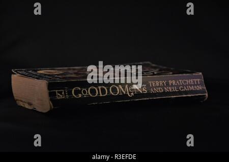 dog eared well worn paperback book , good omens, on dark background. Stock Photo
