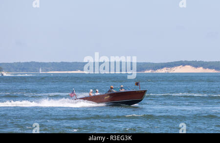 four people on a old wooden power boat enjoying the water Stock Photo