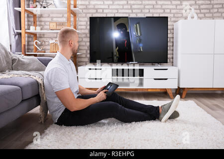 Man Streaming Television Channel Through Wireless Connection On Digital Tablet Stock Photo