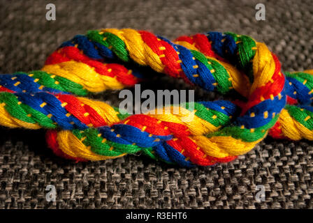 A rainbow colored rope tied into a reef knot Stock Photo