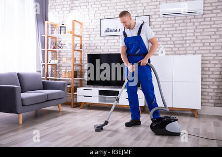 High Angle View Of A Male Janitor Cleaning Floor With Vacuum Cleaner Stock Photo