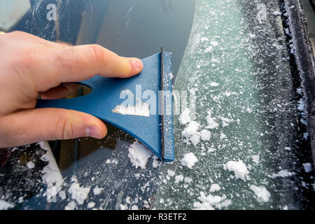 Man outdoor cleaning snow on his car windshield.View from outside of car. Stock Photo