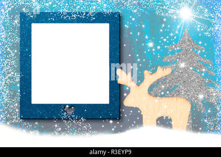 Christmas photo frame card.Wooden reindeer and Christmas tree in snowy landscape with a blank frame for photo or message Stock Photo