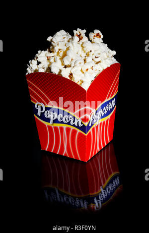 Filled red popcorn box on black background. Stock Photo