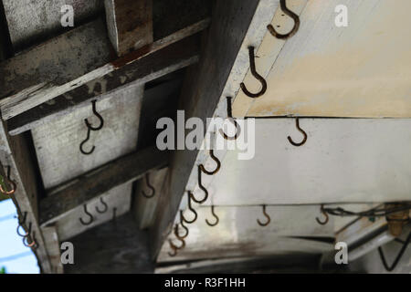 Background surface of old and rusty hooks hanging on the roof Stock Photo