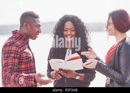A group of young multinational people with a book, students studying in the open air Stock Photo