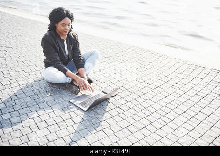 Young woman on the street working on laptop Stock Photo