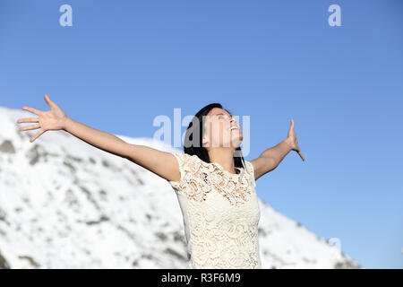 Happy woman breathing deep raising arms in winter Stock Photo