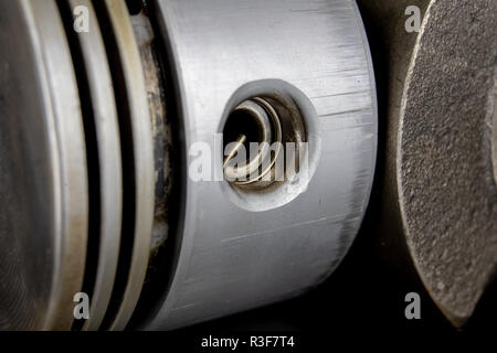 Piston for a four-stroke combustion engine on a metal table. Spare parts for car repair. Dark background. Stock Photo