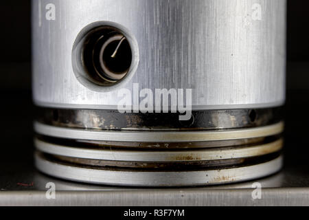 Piston for a four-stroke combustion engine on a metal table. Spare parts for car repair. Dark background. Stock Photo
