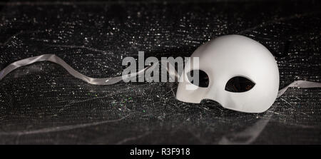 White carnival mask, half face on black shiny background, closeup view, banner Stock Photo