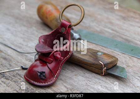 Colorfull leather key ring in the shape of old shoe on wooden background Stock Photo