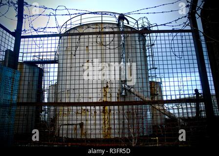 Derelict disused oil storage vessel behind barbed wire in an oil storage depot, Rock Ferry, Merseyside, UK Stock Photo