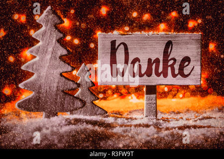 Wooden Sign With German Calligraphy Danke Mean Means Thank You. Christmas Tree On Snow And Fairy Lights In Background. RedSpotlight Stock Photo