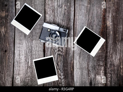 Old film camera and polaroid photos with space for pictures on the wooden background Stock Photo