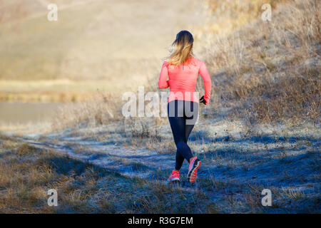 Rear view of young running woman in winter park. Healthy lifestyle background Stock Photo