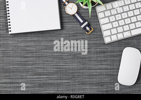 Business composition with white computer keyboard, mouse, coffee cup, women's watch, artificial plant and notebook on grey background. Top view with c Stock Photo