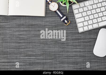 Business composition with white computer keyboard, mouse, coffee cup, women's watch, artificial plant and notebook on grey background. Top view with c Stock Photo