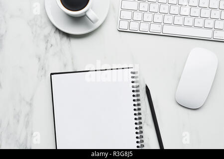 Business composition with white computer keyboard, mouse, coffee cup and notebook with pencil on white marble background. Coffee break at the office c Stock Photo