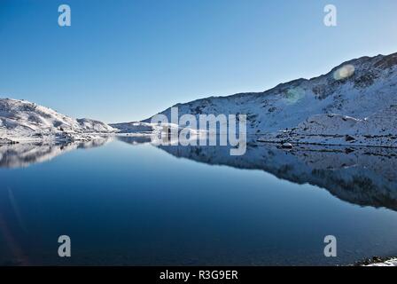 Snow covered hills reflected in a mountain lake, Mount Snowdon, Snowdonia National Park, Gwynedd, North Wales, UK Stock Photo