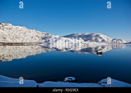 Snow covered hills reflected in a mountain lake, Mount Snowdon, Snowdonia National Park, Gwynedd, North Wales, UK Stock Photo