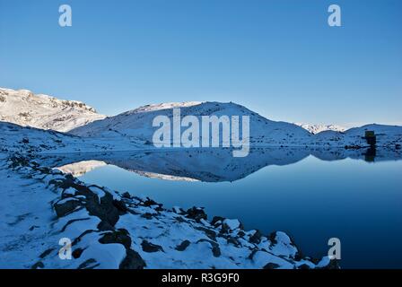 Snow covered hills reflected in a mountain lake, Mount Snowdon, Snowdonia National Park, Gwynedd, North Wales, UK Stock Photo