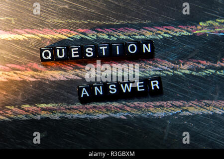 Question Answer on wooden blocks. Cross processed image with blackboard background. Inspiration, education and motivation concepts Stock Photo