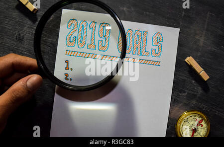 2019 Goals handwritten text on the paper with marker, compass and use magnifying glass on blackboard background. Inspiration, education and celebratio Stock Photo