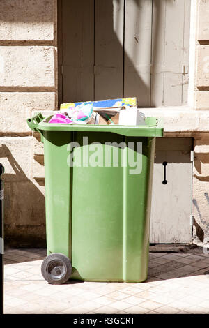 a stuffed to overflowing green wheelie bin in Bordeaux Stock Photo