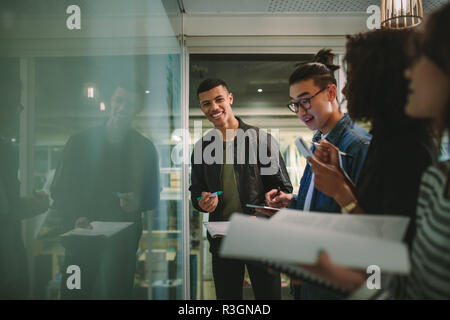Group of students standing together at blackboard with books. Multi-ethnic university students during workshop. Stock Photo