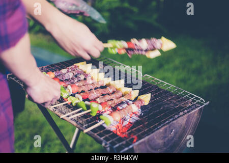 Asian group of friends having outdoor garden barbecue laughing with alcoholic beer drinks on night Stock Photo