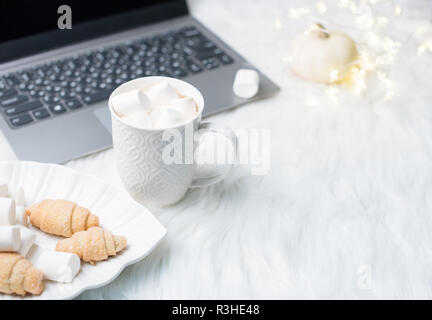 Cozy winter bloggers white work space with laptop, coffee with