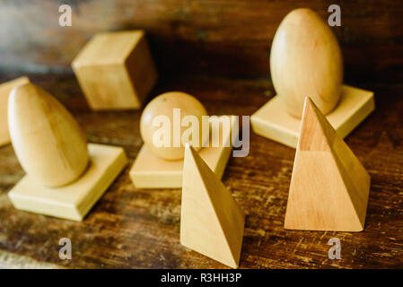 Solid wood shapes to study geometry and volumes, cones, triangles, squares, spheres on a warm wood background. Stock Photo