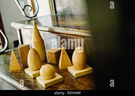 Solid wood shapes to study geometry and volumes, cones, triangles, squares, spheres on a warm wood background. Stock Photo