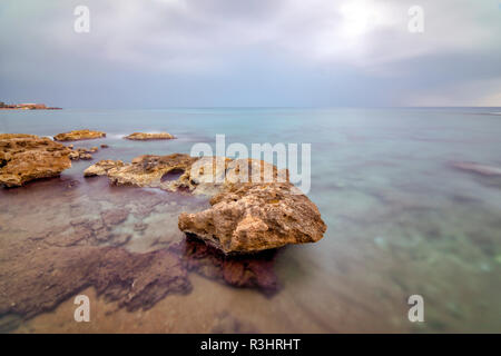Long exposure in Antalya, with brown rocky seaside and cloudy weather. Longexposure time 4 minutes Stock Photo