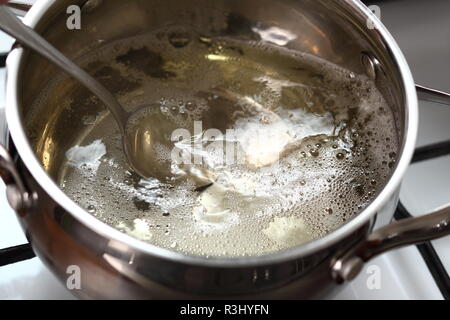 Boiling and Mixing Cider in Pan on Gas Stove. Making Cider Pie Series. Stock Photo