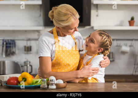 happy grandmother and granddaughter hugging and smiling each other while cooking together Stock Photo