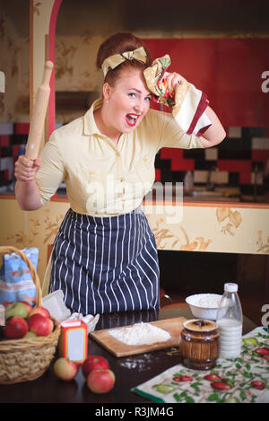 Emotional expressive woman cute woman in the kitchen. In the hands holding tools for cooking food. Stock Photo