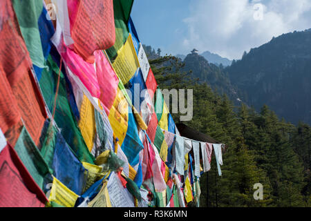 Bhutan, Paro. Colorful prayer flags in front of small outbuilding of the Tiger's Nest, sacred Himalayan Buddhist temple complex. Stock Photo