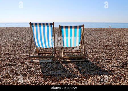 Two Empty Deckchairs and a Seagull on Brighton Beach. UK Stock Photo