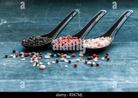 Close up pink himalayan salt and peppers in spoons Stock Photo