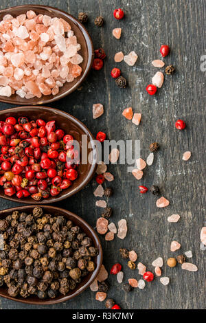Close up pink himalayan salt and peppers in spoons Stock Photo
