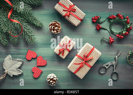 Rustic wooden background in green and red with fir branches and Christmas gifts in simple brown wrapping paper. Seasonal background shot from above. F Stock Photo