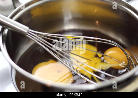 Eggs and melted chocolate in saucepan. Making Chocolate, Pear and Pecan Pie Series. Stock Photo