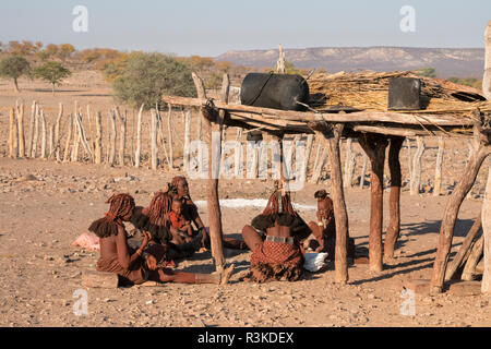 Himba women of one village gather to talk and prepare food in a remote village near Opuwo. Stock Photo