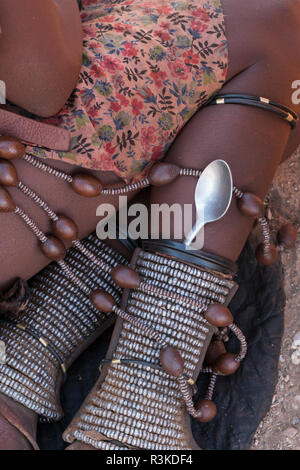 A Himba woman carries her spoon in the ankle adornments she wears all the time, in a remote village near Opuwo, Namibia. Stock Photo