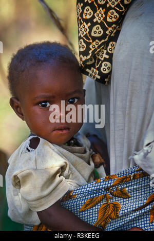 Sub-Saharan Africa, Senegal, A young Bassari tribe girl sits in a wrap on her mothers back. Stock Photo