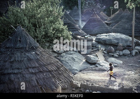 Sub-Saharan Africa, Senegal. A young boy runs through the thatched-roofed huts of the Bedik tribe village of Andyel (Andjel). Stock Photo