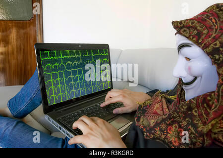 hacker with computer on the couch at home,anonymous mask Stock Photo